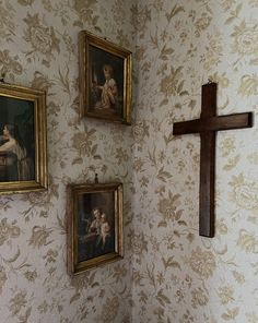 three paintings hang on the wall next to a cross