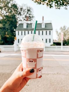 a person holding up a cup with an animal pattern on it and a straw in the other hand