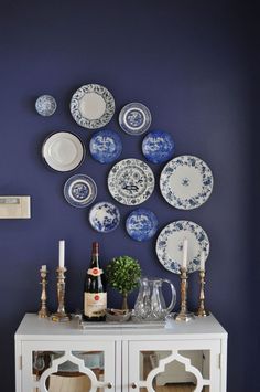 blue and white plates are arranged on the wall above a china cabinet in this dining room