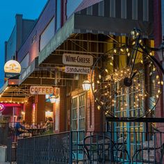 the outside of a wine and cheese shop with lights hanging from it's windows