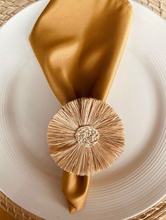 a plate with a gold napkin on top of it and a golden tie around the edge