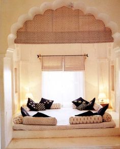 two beds in a room with white walls and curtains on the windowsills are decorated with black and white pillows