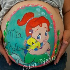 a pregnant woman with her belly painted like a mermaid holding a fish and the words, mia belon, enea tejeda