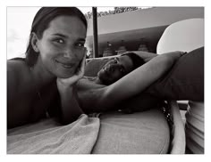 a black and white photo of a woman laying on a couch with her hand under her chin