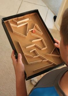 a kid is playing with a wooden board game that looks like it has been made out of cardboard