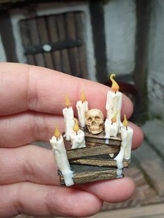 a hand holding a small piece of wood with candles on it and a skull in the middle