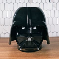 a darth vader helmet sitting on top of a wooden table next to a white tiled wall