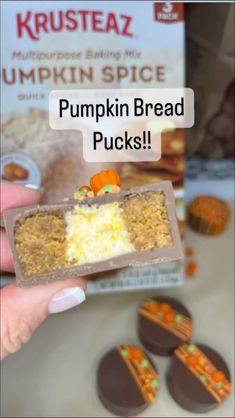 a person holding up a box of pumpkin bread with oranges on it and some cookies in the background