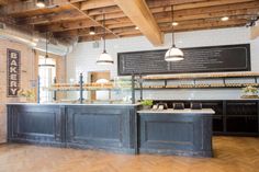 the interior of a bakery with wooden floors and exposed ceilings, along with an island