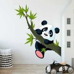 a panda bear sitting on top of a tree branch with bamboo leaves hanging from it's branches