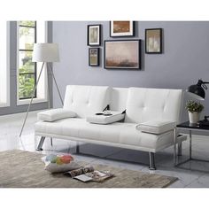 a white couch sitting on top of a rug in a living room next to a table