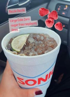 a person holding up a cup with ice cream and strawberries on it in their hand