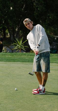 a man standing on top of a green field holding a golf club