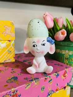 an elephant figurine sitting on top of a pink box next to tulips