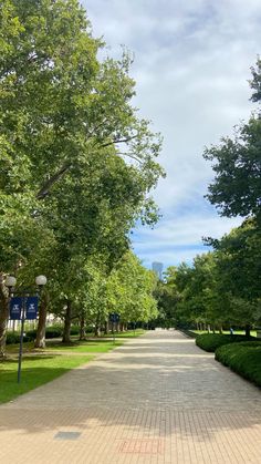 the walkway is lined with green trees and bushes on either side of the path are street lamps