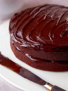 a chocolate cake sitting on top of a white plate with a knife next to it