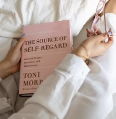 a person laying in bed with a book and glasses on their hands, reading the source of self - regard