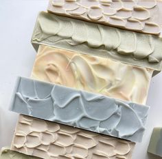 four bars of soap sitting on top of each other with different colors and shapes in them