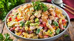 a bowl filled with pasta salad and garnished with parsley on the side