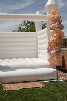 an inflatable couch with balloons attached to it and flowers on the back ground