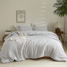 a white bed sitting in a bedroom next to a potted plant and two lamps