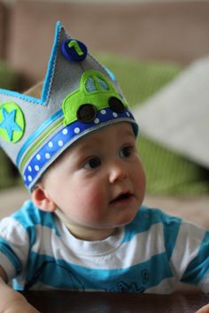 a baby wearing a blue and white striped shirt with a green truck on it's head