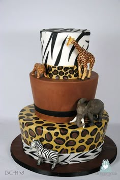 a three tiered cake decorated with zebras, giraffes and elephants