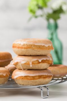 glazed donuts with icing on a cooling rack next to a vase and flowers