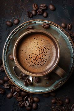 a cup of coffee sitting on top of a saucer surrounded by coffee beans and spoons