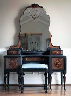 an antique dressing table with mirror and stool in front of it on a hard wood floor