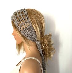 a woman with blonde hair wearing a gray knitted headband and braided ponytail