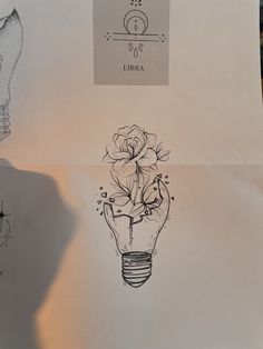 a drawing of a light bulb with flowers in it and a hand holding a pen