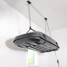 a black object suspended from the ceiling by two wires in a room with white walls