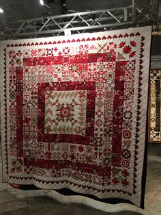 a large red and white quilt hanging from the ceiling