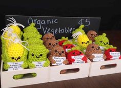 small crocheted fruits and vegetables are on display in white crates with tags attached to them