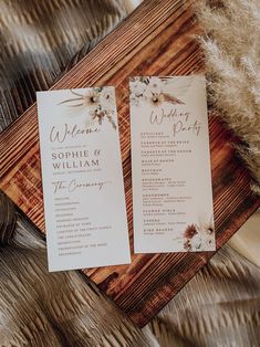 two wedding programs sitting on top of a wooden table