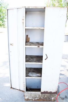 an old white refrigerator sitting on the side of a road