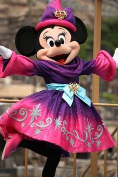 a minnie mouse dressed in a purple and pink dress