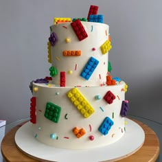 a three tiered cake with legos on it's side and sprinkles all over the top