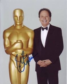 a man in a tuxedo standing next to an oscar statue with his hand on his hip