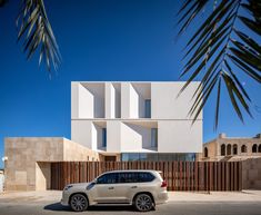 a white car parked in front of a building with large windows and wooden slats