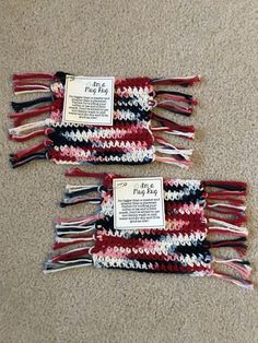 three red, white and black crocheted bags with labels on them sitting on the floor