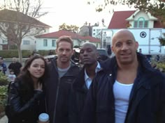 four people posing for a picture in front of some houses with the caption russian