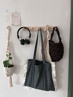 three purses hanging on the wall next to a potted plant and headphones