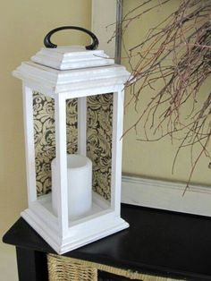 a white candle holder sitting on top of a black table next to a basket and wallpaper