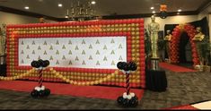 an inflatable backdrop with black and gold balloons on the front, white and red decorations behind it