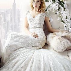 a woman in a white dress is sitting on a window sill and posing for the camera