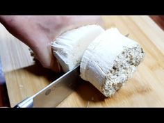 a person is cutting something with a knife on a wooden table next to a piece of bread