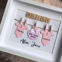 a baby's birth announcement frame with clothes hanging from the clothesline and name tag