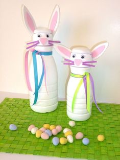 two plastic bottles with bunny ears and ribbons tied around them sitting on a green mat